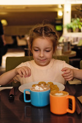 Charming little schoolgirl enjoying a delicious breakfast from the children's menu in a cozy cafe. Useful and nutritious