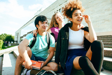 cute group of teenages at the building of university with books huggings, diversity nations students lifestyle