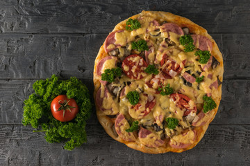 Homemade pizza on the table with herbs and tomatoes. The view from the top.