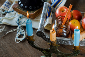 Jewish Holiday Rosh hashanah honey and apples with pomegranate and candles on Prayer Shawl Tallit