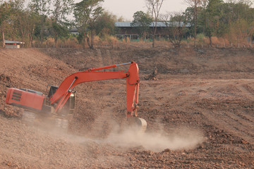 Orange excavator Under construction Large reservoir, Dust by digging the soil.