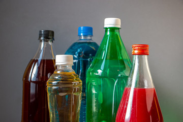 Colored water in the bottles. Closeup photo of plastic and glass bottle with multi-color and size