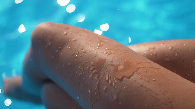 Girl dripping water to her legs. Sexy tan legs of a fit lady in the pool in Slow motion. Awesome summer footage