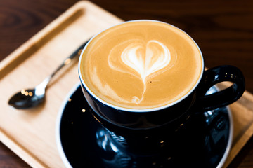 Hot latte coffee serve in dark blue cup with love latte art