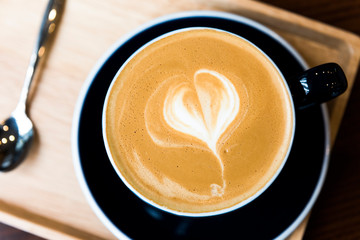 Hot latte coffee serve in dark blue cup with love latte art