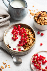 Crunchy granola with natural yogurt and red currant berries. Clean eating, dieting, fitness menu concept. Breakfast food still life