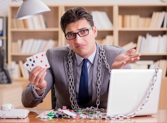 Young businessman addicted to online gambling cards playing in t