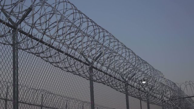 Pan Along Prison Razor Wire at Sunset Outside Jail 4K