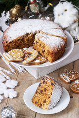Traditional Christmas fruitcake on the background of a box with Christmas toys and fir branches.