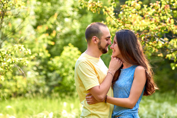 Fototapeta premium Lovers. A young couple. The guy with the girl are walking in the forest. Loving couple hugs sensually. Lovers man and woman in the arms of each other. Romantic walk in the forest. Loving relationship