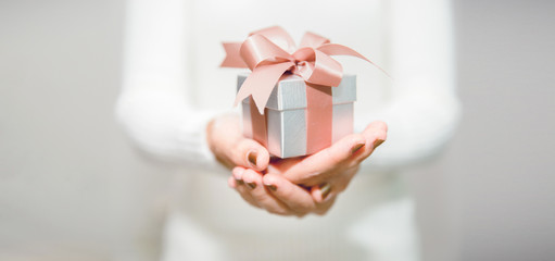 Woman hands with white sweater holding a small gift box for special event with copy space.