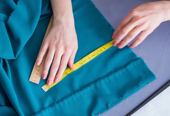 Woman tailor working on a clothing sewing stitching measuring fa