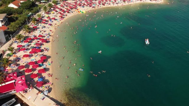 The beach of Klek in Croatia with people bathing and swimming during the main season in summer - aerial shot