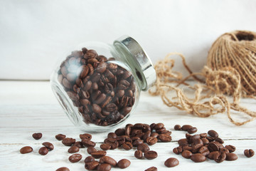 Coffee beans in a glass jar on a light wooden background