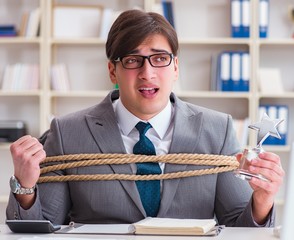 Businessman tied up with rope in office
