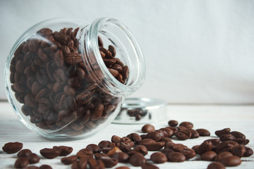 Coffee beans in a glass jar on a light wooden background