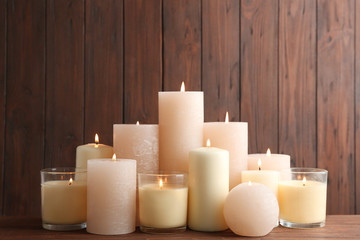 Fototapeta na wymiar Set of burning candles on table against wooden background