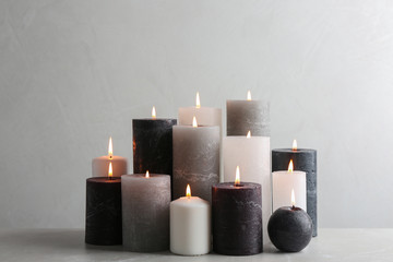 Set of burning candles on table against light background