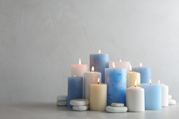 Composition with burning candles on table against light background, space for text