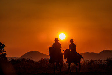 Fototapeta na wymiar Beautiful silhouttle cowboys horse riding during sunset with mountain background