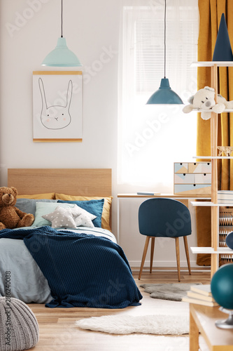 Teddy bear on single wooden bed in blue and orange bedroom interior