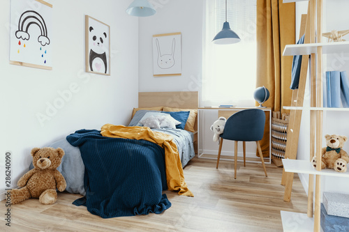 Workspace with desk and chair in elegant teenager's room with blue and orange design