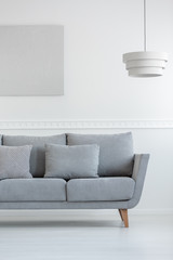 Scandinavian living room sofa in white daily room interior with painting on the wall and lamp above