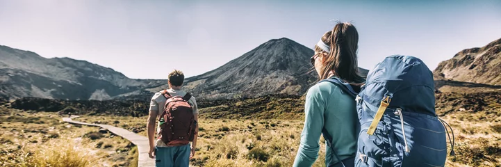 Fotobehang Nieuw-Zeeland Wandelpaar Backpackers Tramping In Tongariro National Park. Mannelijke en vrouwelijke wandelaars wandelen door Mount Ngauruhoe. Mensen die buiten een gezonde actieve levensstijl leiden © Maridav