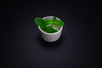 Fresh mint leaves in plate isolated on black background
