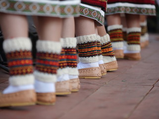 females legs in traditional regional leather folk shoes, woolen socks and lower parts of skirts...