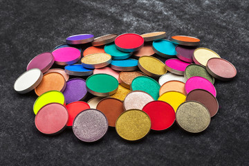 big amount of shimmer and matt colorful circle shaped eye shadows lying on a black background....