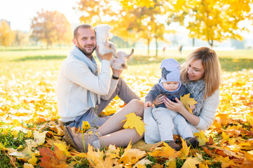 Happy family with their baby outdoor portrait in autumn park.