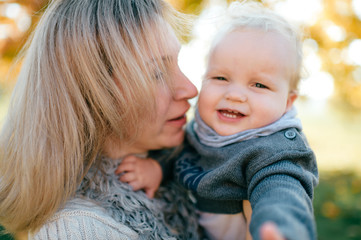 Young smiling woman with her funny child closeup portrait at nature.