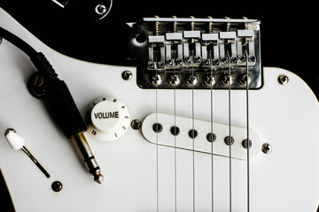 Electronic guitar details close up and wire cable jack. Close up black and white electronic guitar.