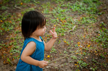 Asian 1 year old toddler is busy playing in a tropical park in the morning. Playing with nature.