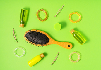 Fototapeta na wymiar Hair care products and styling items on green background. Flat lay style. Women beauty and beauty salon cosmetics concept.