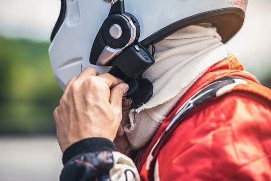 The Racer's Hand Is Wearing A Helmet Strap For Safety In The Race.