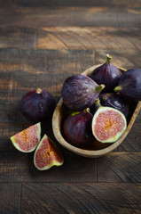 Fresh figs in a wooden bowl on an old wooden background.