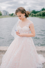 Fototapeta na wymiar Beautiful young bride in white wedding dress holding flower at nature