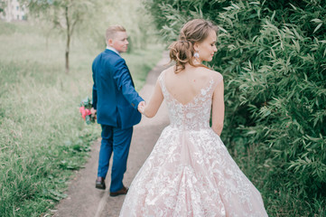 Beautiful wedding couple walking along road at nature