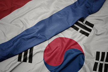 waving colorful flag of south korea and national flag of netherlands.
