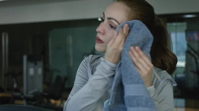 Woman wiping the sweat of her face with a towel after doing sports - sport fitness concept