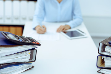 Calculator and binders with papers are waiting to be processed by business woman or bookkeeper back...