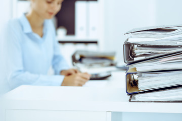 Binders with papers are waiting to be processed by business woman or bookkeeper back in blur....