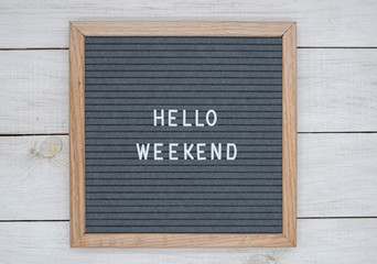 felt board with text in English hello weekend on a white wooden board background