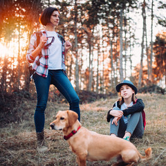 Family with dog resting in forest during sunset