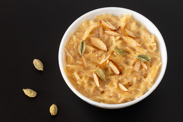 Vermicelli dessert, popular sweet dish know a kheer made with milk and garnish with dry fruits isolated on black gray background, served in bowl. Selective focus. Top view.