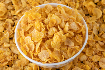 Cornflakes in blowl, healthy corn flakes background a delicious dietary breakfast cereal. Top View.
