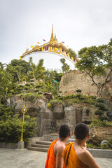  couple of Monks walk past the amazing Wat Saket temple in Bangkok in Thailand. Beautiful golden...