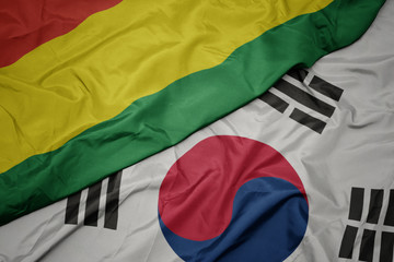 waving colorful flag of south korea and national flag of bolivia.